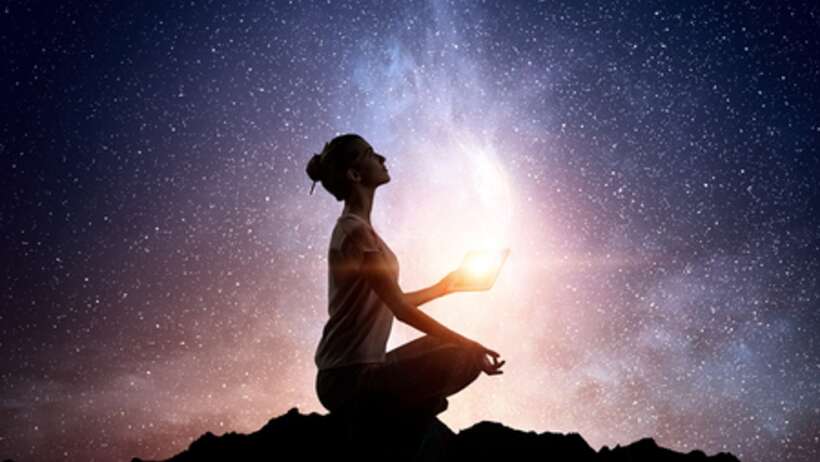 Woman meditating under starry sky, exploring consciousness.