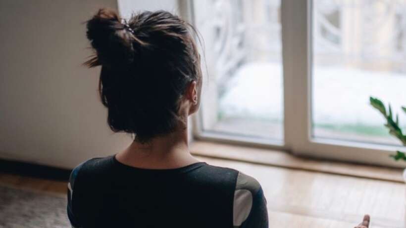 Woman meditating near window, 'Lockdown Meditation'.