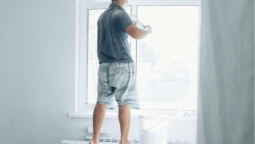 Man painting window with 'Be Yourself' text.