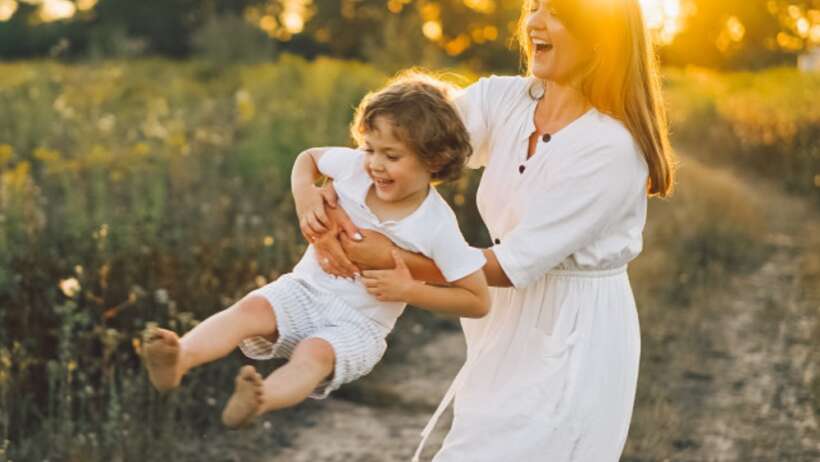 Mother and child playing in a field.