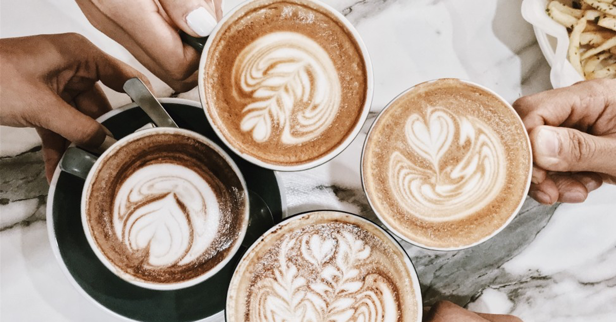 Four coffees with latte art on marble table
