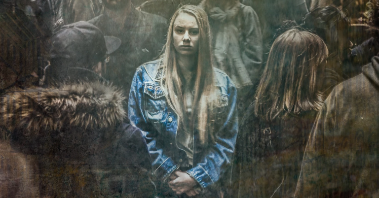 Woman in denim jacket surrounded by people.