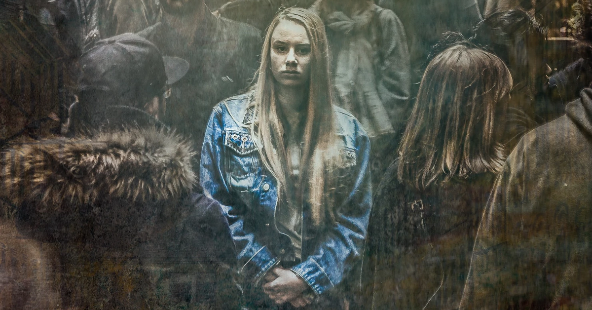 Woman in denim jacket surrounded by people.
