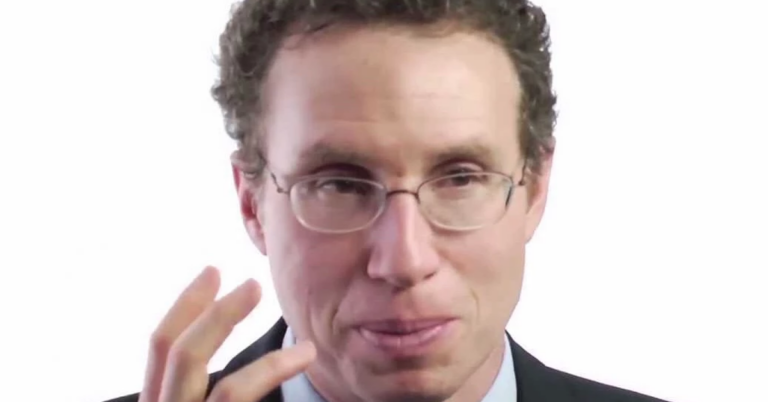 Man in glasses speaking to camera.