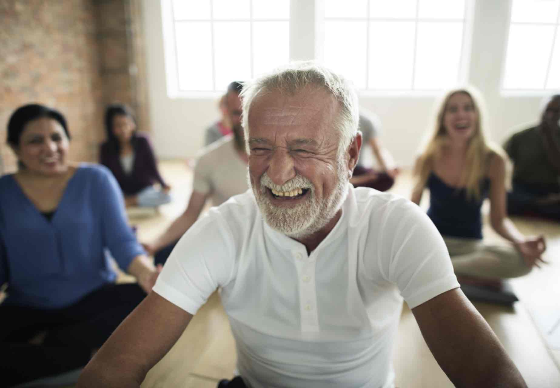Laughing mature man enjoying yoga class.
